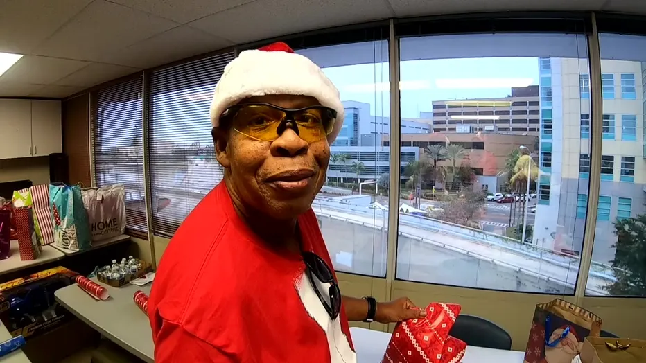 A man in glasses and New Year's clothes opens gifts